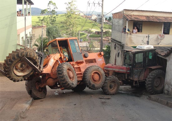 Pá-carregadeira volta em subida e empurra trator sobre  residência