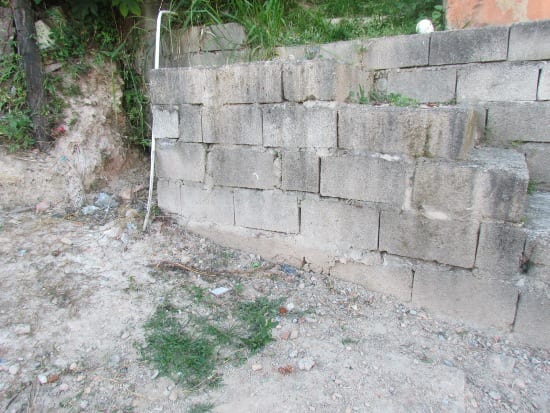 Homem tenta atirar em rapazes e atinge muro de casa