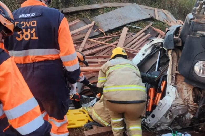 Caminhão carregado com madeira capota na BR-381 e deixa motorista preso às ferragens